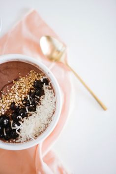 a bowl filled with chocolate and nuts on top of a pink napkin next to a spoon