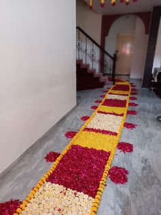 a hallway decorated with red, yellow and white flower petals on the floor next to stairs