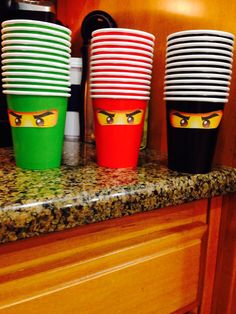 three cups with faces painted on them are sitting on a countertop in a kitchen