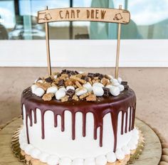 a cake with white frosting and chocolate drizzled on top, topped with marshmallows