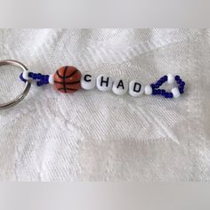 a keychain with beads that say chad and a basketball ball on it, sitting on a white sheet