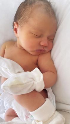 a baby sleeping on top of a white pillow