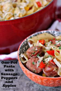 one - pot pasta with sausage, peppers and apples in a red bowl next to another dish