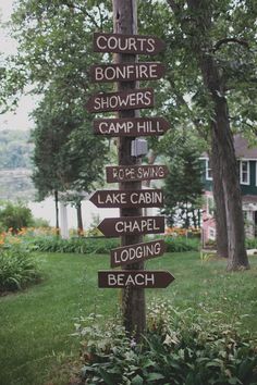 a wooden pole with many signs on it in front of some trees and bushes,