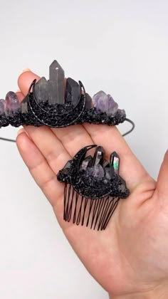 two black hair combs with crystals on them being held by someone's hand