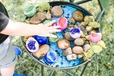 a child's hand reaching for rocks and stones in a bowl