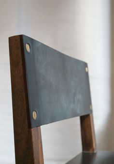 a wooden chair with metal straps on it's back legs and seat padding