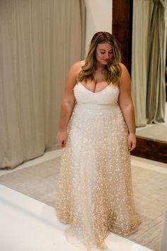 a woman standing in front of a mirror wearing a dress