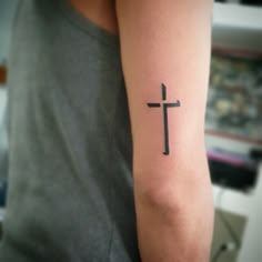 a person with a cross tattoo on their arm