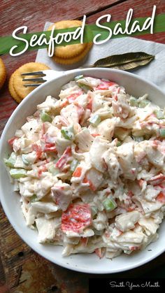 a white bowl filled with seafood salad on top of a wooden table next to cookies