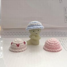 three small crocheted hats sitting on top of a white table next to each other