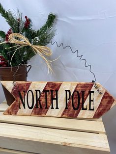 a wooden sign that says north pole on it next to a potted pine tree