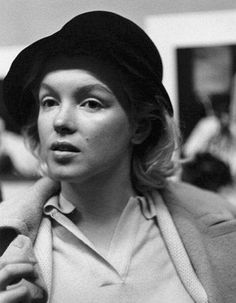 a black and white photo of a woman with a hat on her head looking off to the side