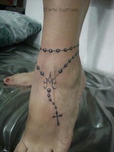 a woman's foot with a rosary and cross tattoo on the side of it