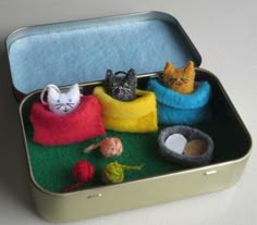 there are three cats sitting in a small box with balls of yarn on the floor