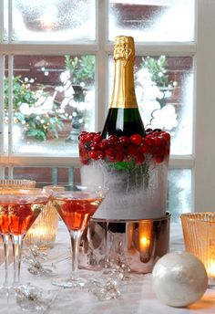 a bottle of champagne sitting on top of a bucket filled with ice and red roses