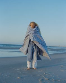 a woman wrapped in a blanket on the beach