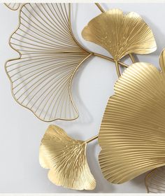 three gold leaf shaped objects on a white surface