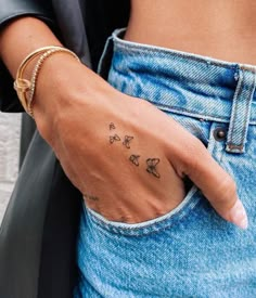 a woman's hand with a small tattoo on her left wrist and butterflies in the pocket