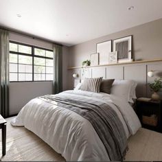 a bedroom with a large bed and two pictures on the wall above it, in front of a window