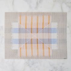 a piece of cloth on top of a marble counter with an orange and blue checkered design