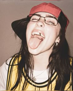 a woman with glasses and a hat making a silly face while wearing a red cap