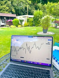 an open laptop computer sitting on top of a metal table in front of a yard