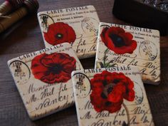 four coasters with red flowers on them are sitting on a table next to some books