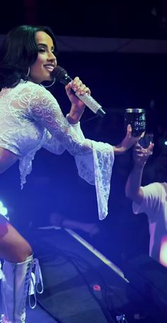 a woman holding a wine glass while standing on top of a stage with other people