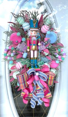 a nutcracker wreath with pink and blue decorations on the front door for christmas