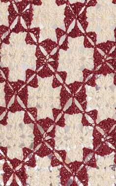 crocheted red and white doily with small flowers on the edges, in an intricate pattern