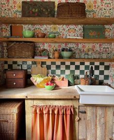 an old fashioned kitchen with floral wallpaper and wooden shelves above the sink, is shown