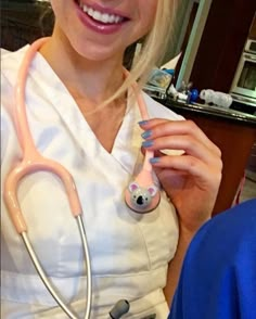 a woman with blond hair wearing a white shirt and stethoscope in her hand