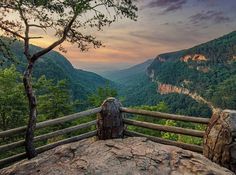 a scenic view of the mountains and valleys from a wooden bench at sunset or dawn