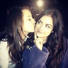 two young women are kissing each other in front of a camera light at the same time