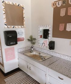 a bathroom sink sitting under a mirror next to a wall mounted paper dispenser