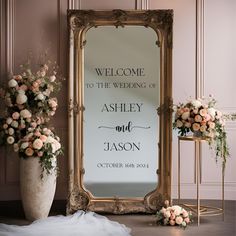 a large mirror sitting on top of a wooden floor next to a vase filled with flowers