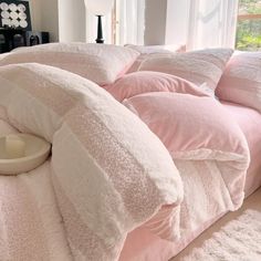 a bed with pink comforters and pillows on it