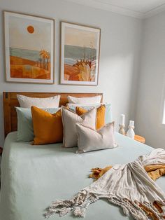 a bed with two pictures above it and blankets on the headboard in front of it