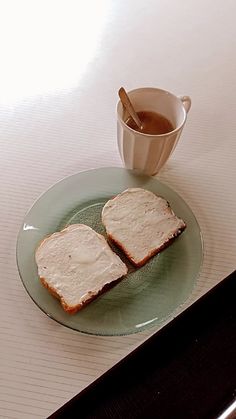 two pieces of bread sitting on top of a green plate next to a cup of tea