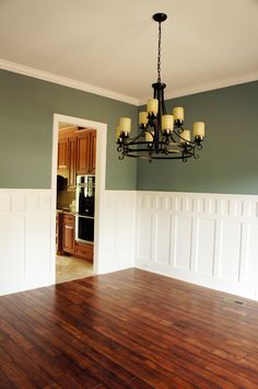 a chandelier hangs from the ceiling in an empty room with hard wood flooring