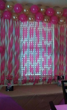 pink and white balloons are hanging from the ceiling above a table with purple linens