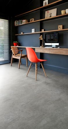 two orange chairs are sitting in front of a desk and bookshelf on the wall