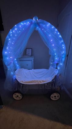 a baby crib with blue lights on the sides and white sheets covering it's canopy