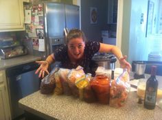 a woman is standing in the kitchen with her arms outstretched and bags of food on the counter