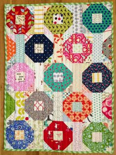 a patchwork quilt on a wooden floor with lots of different colors and shapes in it