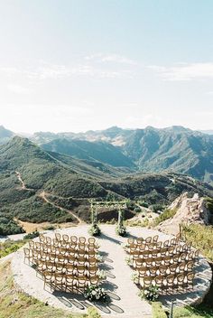 an outdoor ceremony set up on top of a hill with mountains in the back ground