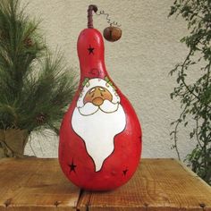 a red and white santa clause pear sitting on top of a wooden table next to a potted plant