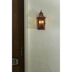 a light that is on the side of a wall next to a door with a number