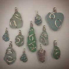 a group of nine sea glass pendants sitting next to each other